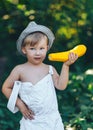 Little boy holding yellow zucchini squash in summer garden farmer boy in white casual robe and hat Royalty Free Stock Photo