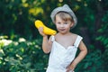 Little boy holding yellow zucchini squash in summer garden farmer boy in white casual robe and hat Royalty Free Stock Photo