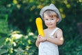 Little boy holding yellow zucchini squash in summer garden farmer boy in white casual robe and hat Royalty Free Stock Photo