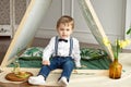 A little boy in holiday clothes is sitting in a tent in his room Royalty Free Stock Photo