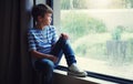 Little boy, home and watching the rain by window of natural water drops and thinking in relax indoors. Child relaxing by Royalty Free Stock Photo