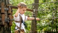Little boy hooking safety rope before passing obstacles at rope adventure park. Kids sports, summer holiday, fun outdoors, scouts Royalty Free Stock Photo