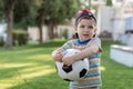 Little boy hugs a soccer ball and plays soccer in the summer in the park on the nature Royalty Free Stock Photo