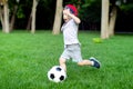 Little boy hugs a soccer ball and plays soccer in the summer in the park on the nature Royalty Free Stock Photo