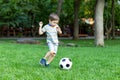 Little boy hugs a soccer ball and plays soccer in the summer in the park on the nature Royalty Free Stock Photo