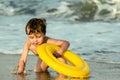 A little boy with an inflatable circle splashing into the sea.