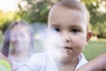 Little boy inflates and bursts soap bubbles. Cute funny kid is playing with soap bubbles in the park. Place for text Royalty Free Stock Photo