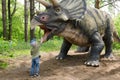 Little boy interacts with dinosaur model Triceratops