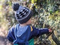 A little boy investigates a hole in the embankment