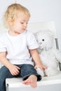 The little boy in jeans with a toy bear sits Royalty Free Stock Photo