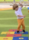 Little boy jumping by hopscotch drawn. Boy playing hopscotch game on playground on spring day. Royalty Free Stock Photo