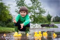 Little boy, jumping in muddy puddles in the park, rubber ducks i Royalty Free Stock Photo