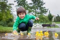 Little boy, jumping in muddy puddles in the park, rubber ducks i Royalty Free Stock Photo