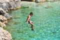 Little boy jumping off cliff into the ocean. Summer fun lifestyle. Brave kid Royalty Free Stock Photo