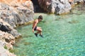 Little boy jumping off cliff into the ocean. Summer fun lifestyle. Brave kid Royalty Free Stock Photo