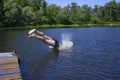 Little boy jumping off headfirst into the river water from the wooden pier