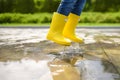Little boy jumping in puddle of water at the summer or autumn day Royalty Free Stock Photo
