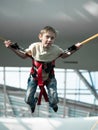 Little boy jumping on the trampoline with rubber ropes