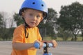 Little boy kid, child in orange t-shirt and blue helmet is riding scooter. Childhood memories, safe and funny experience . Royalty Free Stock Photo
