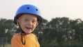 Little boy kid, child in orange t-shirt and blue helmet is riding scooter. Childhood memories, safe and funny experience . Royalty Free Stock Photo