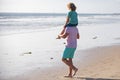 Little boy kid with daddy carrying him on shoulders. Father and son walking on summer beach. Father giving son ride on Royalty Free Stock Photo