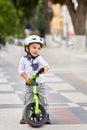 Little boy kid in helmet ride a bike in city park. Cheerful child outdoor. Royalty Free Stock Photo