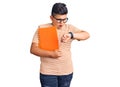 Little boy kid holding book wearing glasses looking at the watch time worried, afraid of getting late Royalty Free Stock Photo