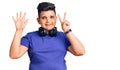 Little boy kid listening to music wearing headphones showing and pointing up with fingers number seven while smiling confident and