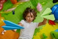 Little boy kid playing paper planes on floor of childcare center