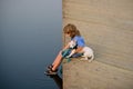 Little boy kid sitting with his dog on lake, child hugging puppy. Child dreaming. Royalty Free Stock Photo