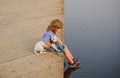 Little boy kid sitting with his dog on lake, child hugging puppy. Child dreaming. Royalty Free Stock Photo