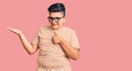 Little boy kid wearing casual clothes and glasses showing palm hand and doing ok gesture with thumbs up, smiling happy and Royalty Free Stock Photo