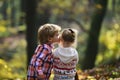 Little boy kiss small girl friend in autumn forest. Brother kiss sister with love in woods. Valentines day concept Royalty Free Stock Photo