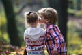 Little boy kiss small girl friend in autumn forest. Brother kiss sister with love in woods. Valentines day concept Royalty Free Stock Photo