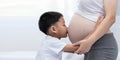 Little boy Kissing the belly of the pregnant mother. Pregnant mother and son are happy. Royalty Free Stock Photo