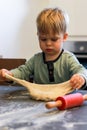 A little boy knead and play with dough, a red rolling pin on the table Royalty Free Stock Photo