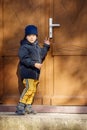 Little boy knocking the brown door in the down city Royalty Free Stock Photo