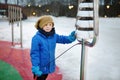 Little boy knocking by street xylophone drums on playground in public park on a snow winter day. Modern equipment of street city Royalty Free Stock Photo