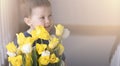 Little boy with a large bouquet of yellow tulips smiling against a sunny background. Royalty Free Stock Photo
