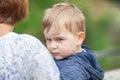 Little boy is leaning against mom`s shoulder, looking whiny Royalty Free Stock Photo