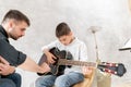 Little boy learn to play guitar while his older brother watches at him