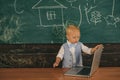 Little boy learning in computer class at primary school. Toddler use laptop computer on classroom chalboard. Pushing