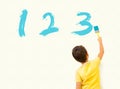 Little boy learning math and painting numbers 123 on the wall