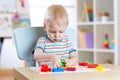 Little boy learning to use colorful play dough in nursery room Royalty Free Stock Photo