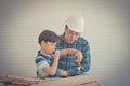 Little Boy learning to work on wood and be a builder from his craftman father in vintage tone