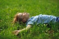 The little boy lies in the field on a green grass. Royalty Free Stock Photo