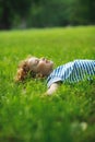 The little boy lies on a green lawn in park. Royalty Free Stock Photo