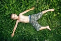 A little boy lies with her arms outstretched on the green grass Royalty Free Stock Photo