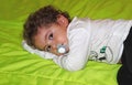 A little boy lies with a pacifier