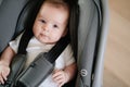 a little boy lies strapped in a stroller-carrier.